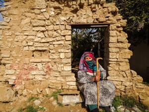 An elderly Palestinian woman sits by a wall of a demolished building near her house in Gaza City on February 6, 2021. Mohammed ABED / AFP