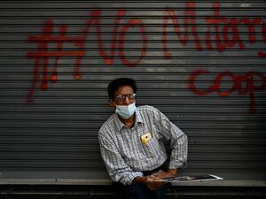 A protester sits in front a graffiti during a demonstration against the military coup in Yangon on February 9, 2021. Ye Aung THU / AFP