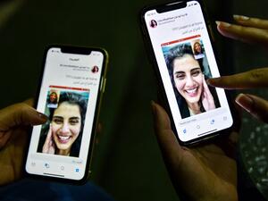 This picture taken February 10, 2021 in Saudi Arabia's capital Riyadh shows a woman viewing a tweet posted by the sister of Saudi activist Loujain al-Hathloul, Lina, showing a screenshot of them having a video call following Hathloul's release after nearly three years in detention. Saudi authorities on February 10 released the prominent women's rights activist, her family said, as the kingdom comes under renewed US pressure over its human rights record. Hathloul, 31, was arrested in May 2018 with about a do