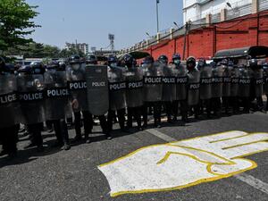Riot police stand guard on a road, behind a street mural of the protesters' three finger salute, after a clash between pro-junta supporters and anti-military coup protesters in Yangon on February 25, 2021. Ye Aung Thu / AFP