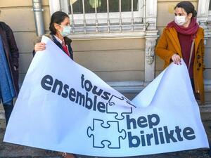 Two women hold a banner reading “All together” as Galatasaray University’s French teachers without working permits give a press conference in front of Galatasaray university in Istanbul on February 23, 2021. (AFP)