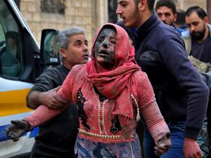 Syrian men help a wounded woman covered in dust 