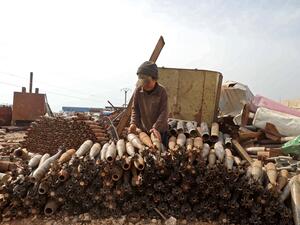 A Syrian child stacks neutralised mortar shells at a metal scrapyard on the outskirts of Maaret Misrin town in Idlib