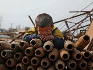 A Syrian child poses atop a stack of neutralised shells at a metal scrapyard