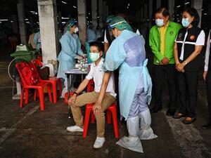Officials watch as a man is inoculated with the CoronaVac vaccine
