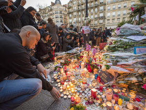 A man lights a candle in front of the theater Le Bataclan in tribute to victims of the  terrorist attack in Paris