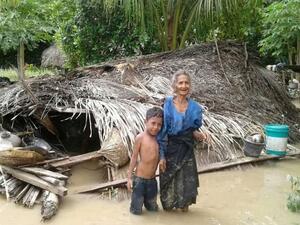 An elderly villager and her grandson in floodwaters