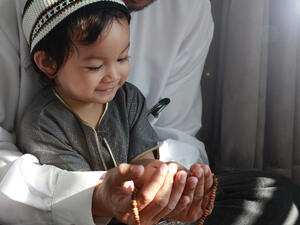 Asian Muslim Man teaching his little son to pray to God 