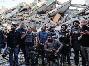 يقفون على حطام مكاتبهم , بعدما قصفت طائرات الاحتلال البرج الذي يتواجد فيه مكاتب الصحافة المحلية والدولية .
