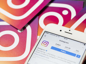 An apple iPhone showing the instagram application alongside other instagram printed logos