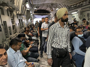 Indian Nationals sit aboard an Indian military aircraft 
