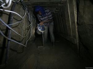 A Palestinian tunnel worker uses a bucket in underground tunnel