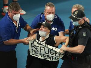  الفتاة تحمل لافتة كتب عليها "أوقفوا احتجاز اللاجئين"