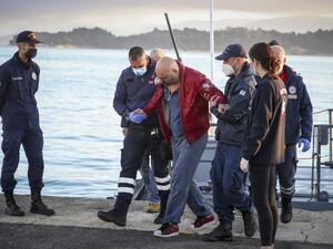 A passenger is helped off the Euroferry Olympia by rescuers and coast guard officers as he arrives at the port of Corfu, on February 18, 2022.  (Photo by Stamatis KATAPODIS / Eurokinissi / AFP) ferry fire
