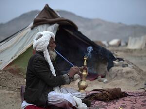 An Afghan internally-displaced man smokes chilam in front of his tent at Shaidayee refugee camp in Injil district of Herat province on February 20, 2022. (Photo by WAKIL KOHSAR / AFP) Western fund freeze on Afghanistan risks humanitarian disaster