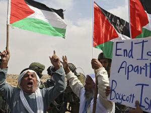 Elderly Palestinians chant slogans in front of Israeli soldiers