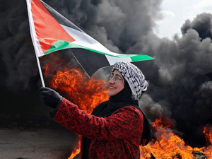Palestinian woman holds up a national flag 