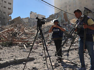  Journalists stand next to the rubble of Al-Jalaa Tower in Gaza 
