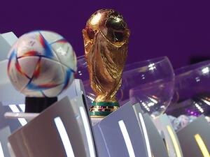 The FIFA World Cup trophy and the official 2022 World Cup ball called Al-Rihla, which means "the journey" in Arabic, are seen on stage during the draw for the 2022 World Cup in Qatar at the Doha Exhibition and Convention Center on April 1, 2022. (Photo by KARIM JAAFAR / AFP)