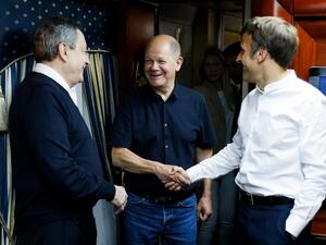 French President Emmanuel Macron (R) shakes hands with German Chancellor Olaf Scholz (C) next to Italian Prime Minister Mario Draghi (L) as they travel on board a train bound to Kyiv after departing from Poland on June 16, 2022. (Photo by Ludovic MARIN / POOL / AFP) French President