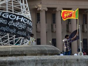 A man waves Sri Lanka's national flag outside presidential secretariat in Colombo on July 13, 2022. Sri Lanka is mired in a deep political and economic crisis, and on July 13, the country's president flew out of the country days after a huge crowd of protesters stormed his residence. (Photo by Arun SANKAR / AFP) Sri Lanka
