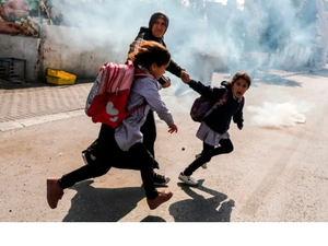 Palestinian mon and her kids run away from the gas canisters 