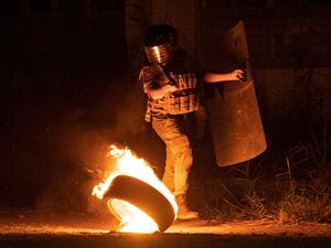A member of Iraqi security deploys near burning tyres amid clashes with protesters during a rally to mark three years since nationwide demonstrations erupted against endemic corruption, in the southern city of Basra, on October 1, 2022. (Photo by Hussein Faleh / AFP) government building