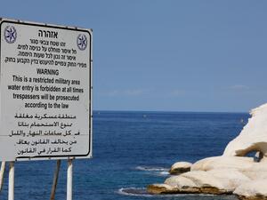 A sign written in Hebrew, English and Arabic designating a military area, stands overlooking the Mediterranean Sea in Israel's Rosh Hanikra, at the border between Lebanon and Israel, on October 7, 2022.(Photo by JALAA MAREY / AFP) gas deal
