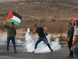 A Palestinian protester returns a tear gas canister amid clashes