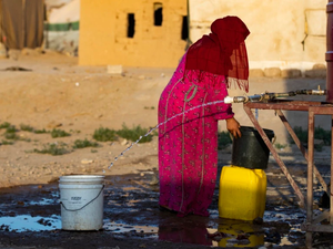 A Syrian woman fills a container with water