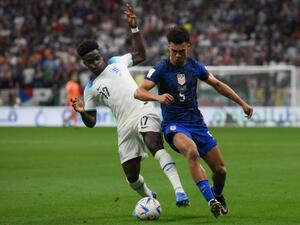 England's forward #17 Bukayo Saka (L) and USA's defender #05 Antonee Robinson fight for the ball during the Qatar 2022 World Cup Group B football match between England and USA at the Al-Bayt Stadium in Al Khor, north of Doha on November 25, 2022. (Photo by Paul ELLIS / AFP)