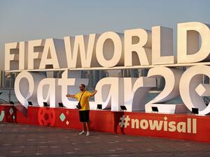 A man (C) has his photos taken with a FIFA World Cup sign in Doha on November 16, 2022, ahead of the Qatar 2022 World Cup football tournament. (Photo by Adrian DENNIS / AFP)