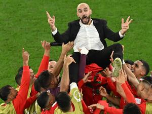 Morocco's players throw Morocco's coach Walid Regragui in the air as they celebrate at the end of the Qatar 2022 World Cup round of 16 football match between Morocco and Spain at the Education City Stadium in Al-Rayyan, west of Doha on December 6, 2022. (Photo by Glyn KIRK / AFP)