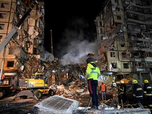 Rescuers work on a residential building destroyed after a missile strike, in Dnipro on January 15, 2023. (Photo by SERGEI CHUZAVKOV / AFP) residential building