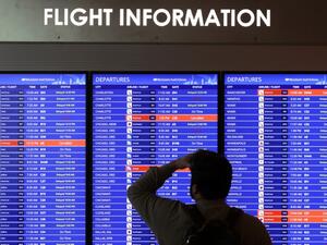 A traveler looks at a flight information board at Ronald Reagan Washington National Airport on January 11, 2023 in Arlington, Virginia. Alex Wong/Getty Images/AFP Conspiracy theories