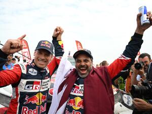 Toyota's driver Nasser Al-Attiyah (R) of Qatar and his co-driver Mathieu Baumel of France celebrate their victory after winning the Dakar Rally 2023, at the end of the last stage between between Al-Hofuf and Dammam, Saudi Arabia, on January 15, 2023. Qatari driver Nasser Al-Attiyah won his fifth Dakar Rally driver's title and second in a row today after the iconic test of endurance finished in Dammam, Saudi Arabia. (Photo by FRANCK FIFE / AFP)