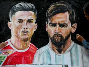 An art school student gives final touches to painting of football players Portugal's Christiano Ronaldo (L) and Argentina's Lionel Messi ahead of the Qatar 2022 World Cup football tournament in Mumbai on November 18, 2022. (Photo by INDRANIL MUKHERJEE / AFP)