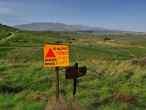 علامة تحذير صفراء من خطر الألغام على سياج من الأسلاك الشائكة في مرتفعات الجولان المحتل