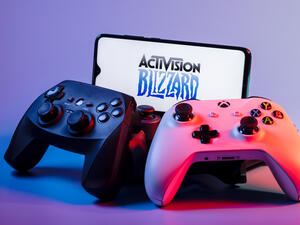August 7, 2021: Activision Blizzard, Inc. is an American video game holding company. A smartphone with the Activision Blizzard logo on the screen on the pile of the gamepads.