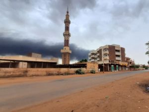 Smoke rises above buildings behind a nearly deserted street in Khartoum. (Photo by AFP) Khartoum