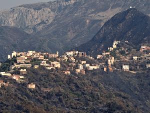 Burnt woodland surrounds a mountain town due to forest fires in the Ait Daoud area of northern Algeria, on August 13, 2021. (Photo by RYAD KRAMDI / AFP) Algeria