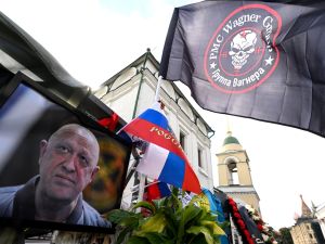 Flag bearing the logo of private mercenary group Wagner flutters above a portrait of late head of Wagner paramilitary group, Yevgeny Prigozhin at a makeshist memorial in Moscow, on August 27, 2023. (Photo by NATALIA KOLESNIKOVA / AFP) Wagner group leader Yevgeny Prigozhin