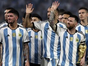 Argentina's forward Lionel Messi (R) waves at the crowd while holding a replica of the World Cup trophy next to his teammates during a recognition ceremony for the World Cup-winning players, following the friendly football match between Argentina and Curacao at the Madre de Ciudades stadium in Santiago del Estero, in northern Argentina, on March 28, 2023. (Photo by Alejandro PAGNI / AFP)