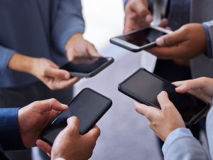 businesspeople standing together in the office and using their cellphones.