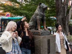 People posing for photos next to the statue of "Hachiko" in front of Shibuya station in central Tokyo