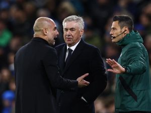 Manchester City's Spanish manager Pep Guardiola (L) and Real Madrid's Italian coach Carlo Ancelotti (C) speak with an official during the UEFA Champions League quarter-final second-leg football match between Manchester City and Real Madrid, at the Etihad Stadium, in Manchester, north-west England, on April 17, 2024. (Photo by Darren Staples / AFP)