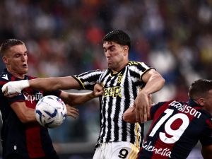 Juventus Serbian forward Dusan Vlahovic (C) fights for the ball with Bologna Swiss midfielder Michel Aebischer (L) and Bologna Scottish midfielder Lewis Ferguson during the Italian Serie A football match Juventus vs Bologna on August 27, 2023 at the “Allianz Stadium” in Turin. (Photo by MARCO BERTORELLO / AFP)