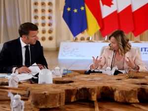 French President Emmanuel Macron (L) speaks with Italy's Prime Minister Giorgia Meloni 