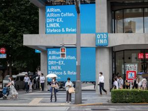 People wait to cross a street outside a branch of the Fast Retailing clothing brand Uniqlo along a street in Tokyo on July 11, 2024. (Photo by Yuichi YAMAZAKI / AFP) Japan