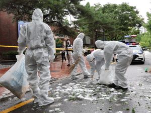 South Korean officials clean up the contents of a trash-carrying balloon sent by North Korea after it landed on a street in Seoul on July 24, 2024. (Photo by YONHAP / AFP) South Korea